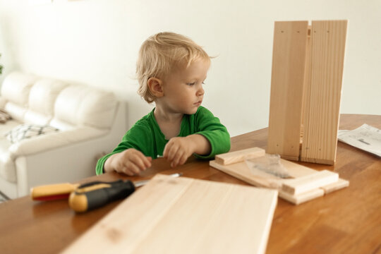 Boy sitting with incomplete wooden box at table in living room