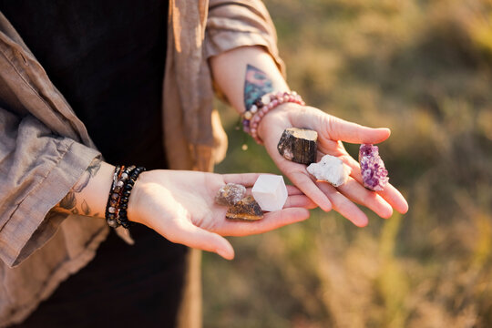 Hands of woman holding natural stones at field