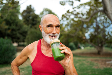 Smiling senior man drinking fresh green smoothie