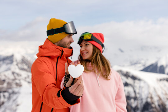 Smiling couple showing heart made of snow