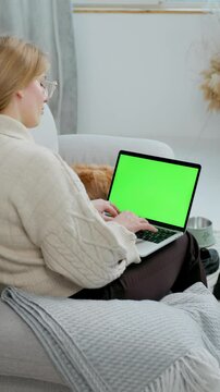 Young Woman Using Green Screen Laptop While Sitting at Home on Couch with Her Pet Dog English Cocker Spaniel. Close up Laptop with Green Mock-up Screen