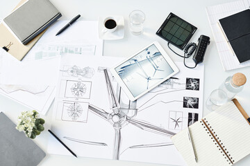 Blueprint of wind turbine kept on table with office supplies