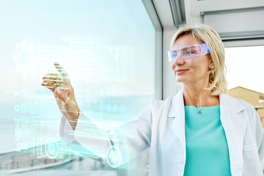 Scientist with virtual glasses touching virtual screen in lab