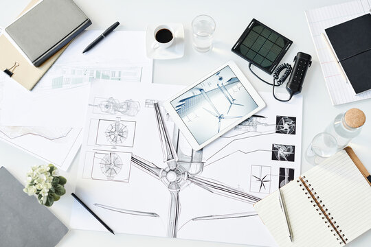 Blueprint of wind turbine kept on table with office supplies