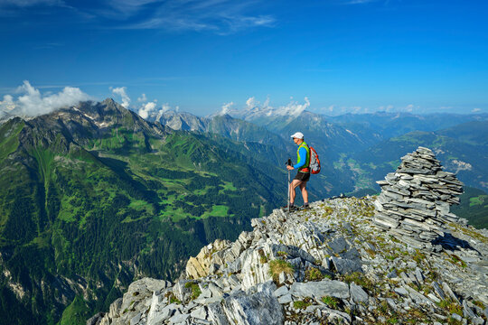 Hikker standing on cliff of Brandberger Kolm mountain near rock cairn under blue sky