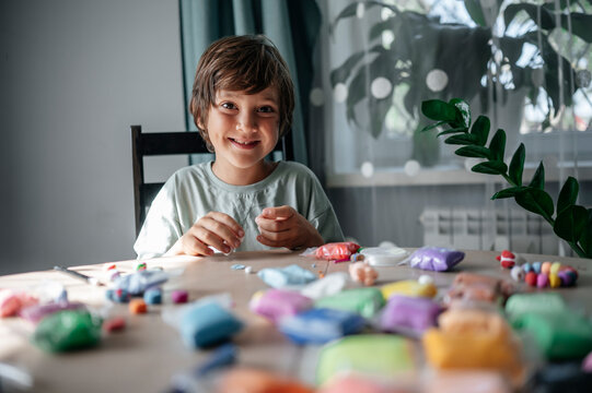 Happy boy playing with multi colored clay at table