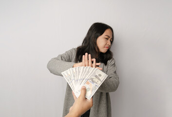 A woman holding up her hand in a stop gesture as someone offers her money She looks disgusted