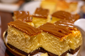 Cheesecake plate with caramel topping on top. The cheesecake are cut into squares and arranged on a white plate
