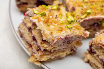 Slice of cake with nuts on top. The cake is cut into pieces and is sitting on a white plate