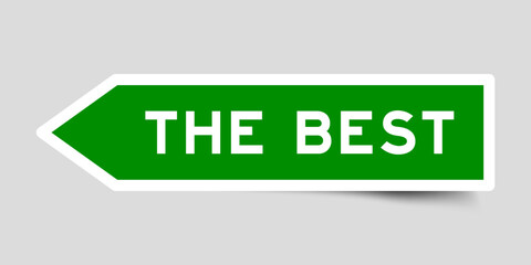 Green color arrow shape sticker label with word the best on gray background