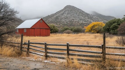 Red barn in snowy autumn field with mountain.