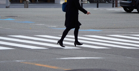 冬の朝の大都市の街の横断歩道を渡る通勤中の女性の姿