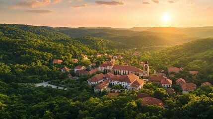 Fototapeta premium Panoramic aerial view of a picturesque village nestled in a valley at sunset, with surrounding forests and rolling hills.