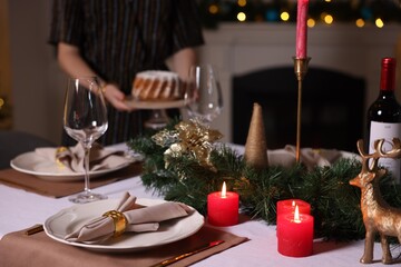 Woman setting table for Christmas dinner at home, selective focus