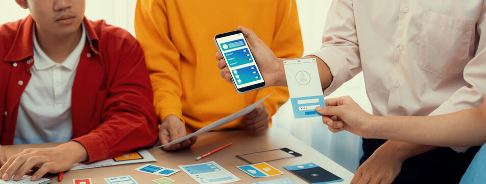 Panorama banner of startup UX developer or company employee design user interface or UI prototype for mobile application or website software with software display on smartphone in office. Synergic - Powered by Adobe