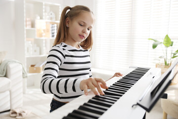 Cute girl playing synthesizer at home. Electronic musical instrument