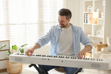 Smiling man playing synthesizer at home. Electronic musical instrument