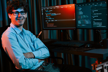 Working IT developer looking at camera with online software development information at neon light...