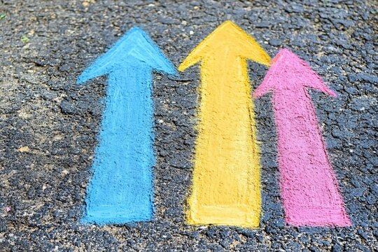 Colorful Chalk Arrows on Asphalt Surface Indicating Growth and Progress in Life