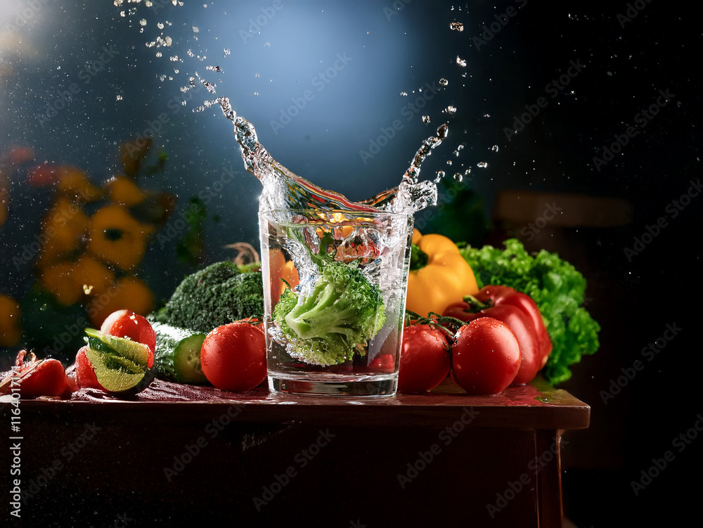 Poster a glass of water splashes dramatically as a broccoli floret is dropped in. surrounding it are vibran
