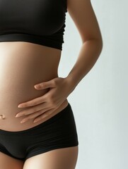 Fototapeta premium Pregnant Woman Gently Touching Baby Bump in Comfortable Setting