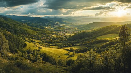 Obraz premium Stunning panoramic view of lush green alpine mountains under dramatic sky at sunset with valley and village in the distance