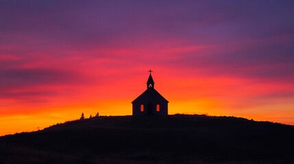 Fototapeta premium Silhouette of a small church on a hilltop at sunset, vibrant colors of orange and purple.