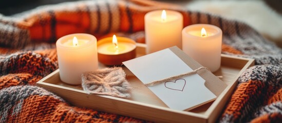 Cozy wooden tray with glowing candles and a heartfelt card on a soft orange plaid blanket creating a warm inviting atmosphere