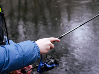 Someone fishing in a lake. Spinning rod. Close-up. Lifestyle, hobby.