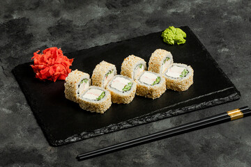 Sushi rolls, red pickled ginger and wasabi on black tray © Tural