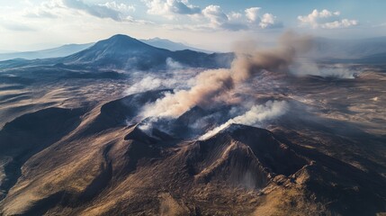 Aerial view of smoke emitting from volcanic cones in a dramatic mountainous landscape under a cloudy sky