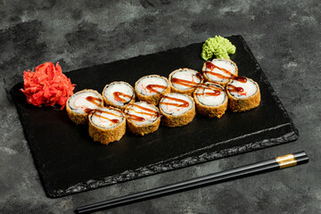 Sushi rolls, red pickled ginger and wasabi on black tray