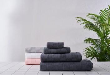 Fototapeta premium Grey towel is on the table and plant background white wall.