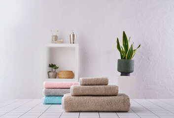 Obraz premium Brown and colored towel close up in o row, white wall and cabinet background wall, bathroom object.