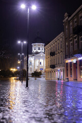 Fototapeta premium Rainy Night in the Old Town Square. Old cobblestone street and church