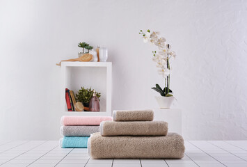 Obraz premium Brown and colored towel close up in o row, white wall and cabinet background wall, bathroom object.