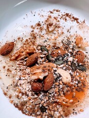 Raw egg in dish with uncooked oats, nuts and seeds sprinkled with cinnamon
