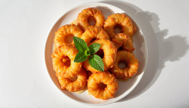 Close-up of golden picarones garnished with mint leaves on a white plate