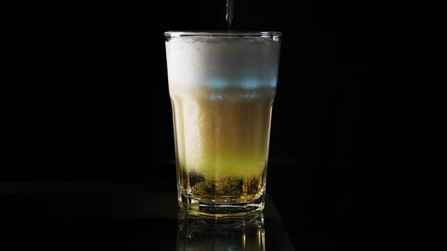 slow motion of pouring beer drink into glass, placed on black background.