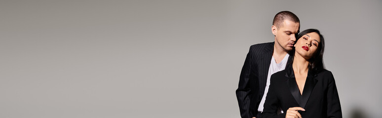 A beautiful young couple dressed in fashionable attire expresses love and connection in a studio, banner