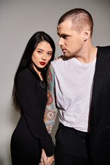 A beautiful young couple showcases their love while dressed elegantly in a studio setting.