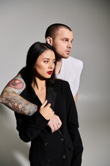 A beautiful young couple dressed in fashionable attire enjoys a romantic moment together.