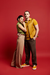 A young couple dressed in fashionable outfits shares a tender moment in a vibrant studio.