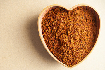 Fresh ground coffee  displayed in a rustic heart-shaped bowl.