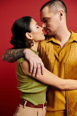 A young couple shares a romantic moment in a studio, showcasing their fashionable outfits.