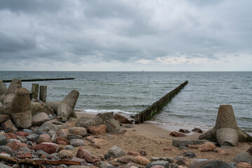 View of wooden breakwaters and concrete tetrapods on the shore of the Baltic Sea on a cloudy summer day, Svetlogorsk, Kaliningrad region, Russia