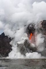 Lava tube flowing into ocean in Hawaii at dawn shows the extremely hot steal formed when the hot...