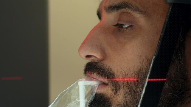 This video shows a close-up of the mouth and jaw area on a dental tomography (CBCT) machine. The red exposure light is clearly visible.