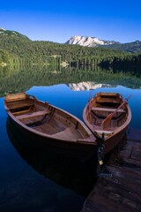 Obraz premium Wooden boats on a tranquil lake with mountain view.