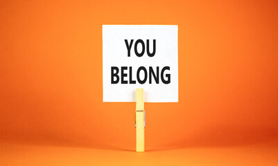 Belonging and you belong symbol. Concept words You belong on beautiful white paper on wooden clothespin. Beautiful orange background. Business belonging and you belong concept. Copy space.